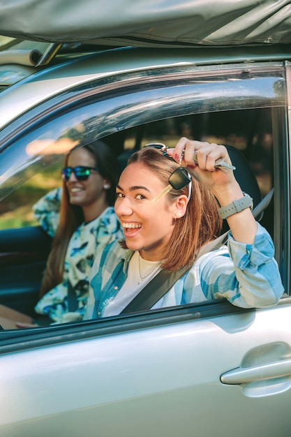 Foto retrato de mujer joven feliz mostrando las llaves del coche nuevo con su amiga lista para iniciar un viaje. concepto de tiempo libre femenino.