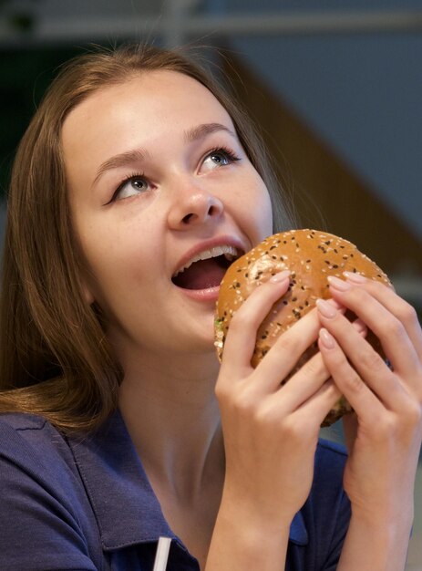 Foto retrato de una mujer joven feliz o una hermosa adolescente comiendo comida chatarra rápida, una hamburguesa sabrosa y