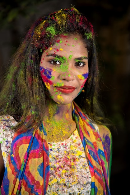 Retrato de una mujer joven feliz con un rostro colorido con motivo del festival de color Holi.