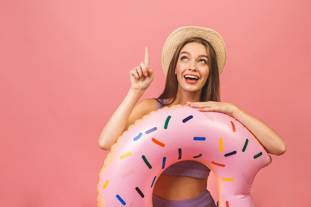 Retrato de una mujer joven feliz vestida en traje de baño saltando y sosteniendo nadar anillo inflable