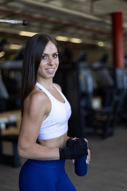 Retrato de mujer joven fitness sonriendo a la cámara en el gimnasio