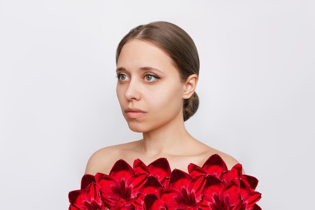 Retrato de mujer joven con flores de lirio de color rojo en lugar de ropa aislado sobre fondo blanco.