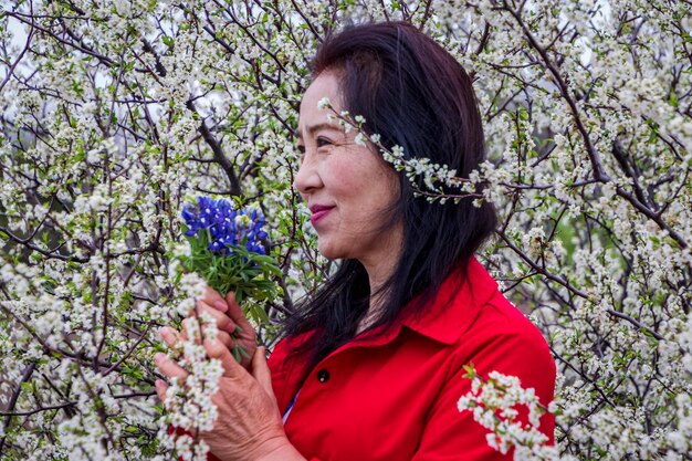 Foto retrato de una mujer joven con flores rojas contra los árboles