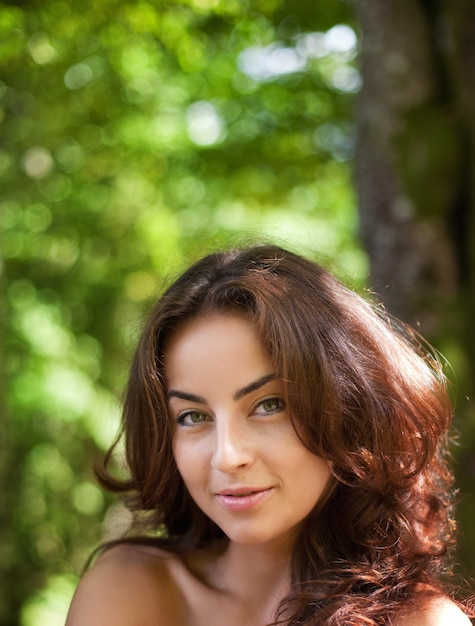 Foto retrato de una mujer joven en el fondo del bosque borroneada