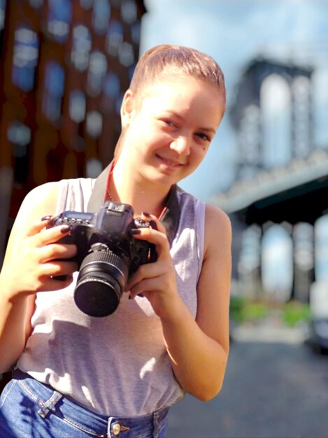 Retrato de una mujer joven fotografiando con una cámara