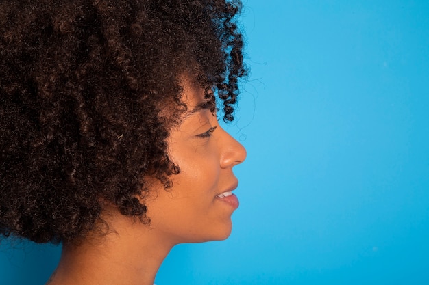 Retrato de mujer joven fresca riendo contra la pared azul