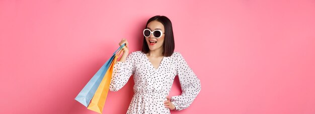 Retrato de una mujer joven con gafas de sol contra un fondo amarillo