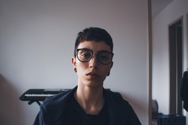 Retrato de una mujer joven con gafas de sol contra la pared