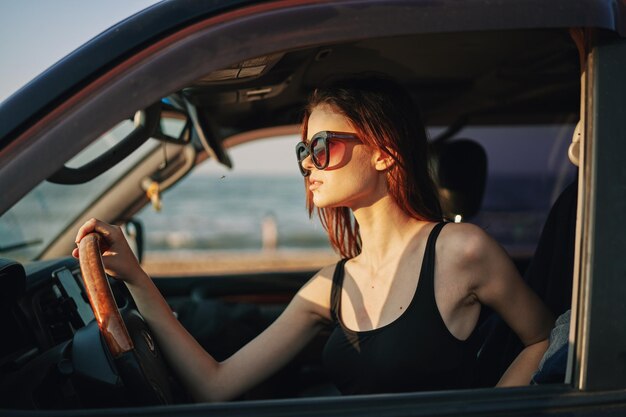 Foto retrato de una mujer joven con gafas de sol mientras está sentada en el coche