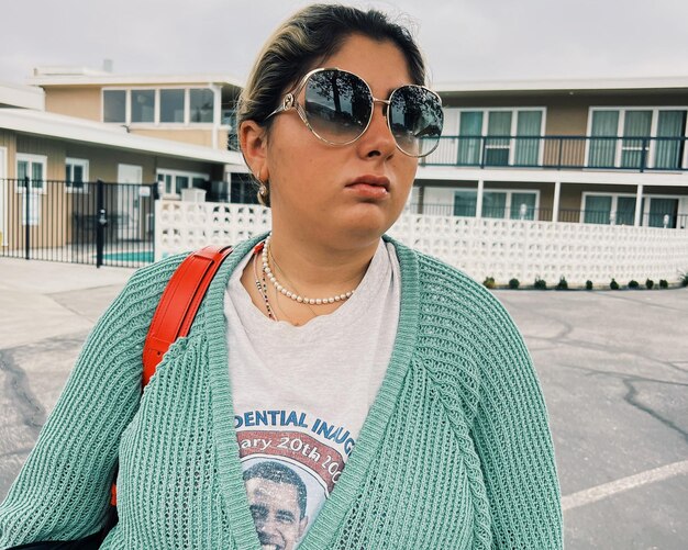 Retrato de una mujer joven con gafas de sol de pie en la ciudad