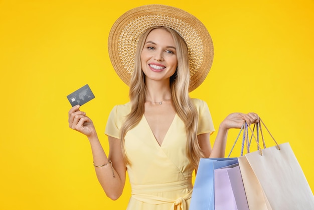 retrato, de, mujer joven, en, gafas de sol, tenencia, tarjeta de crédito, y, bolsas de compras