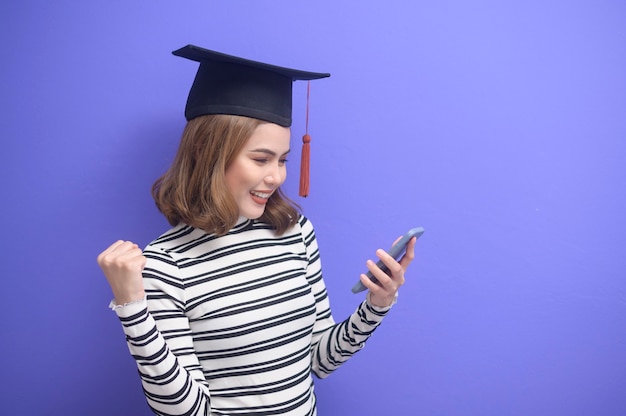 Un retrato de mujer joven graduada sobre fondo azul.