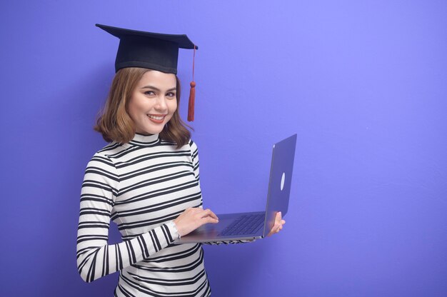 Un retrato de mujer joven graduada sobre fondo azul.