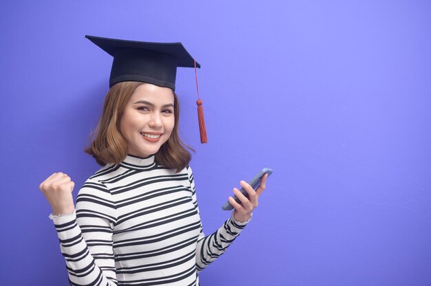 Un retrato de mujer joven graduada sobre fondo azul.