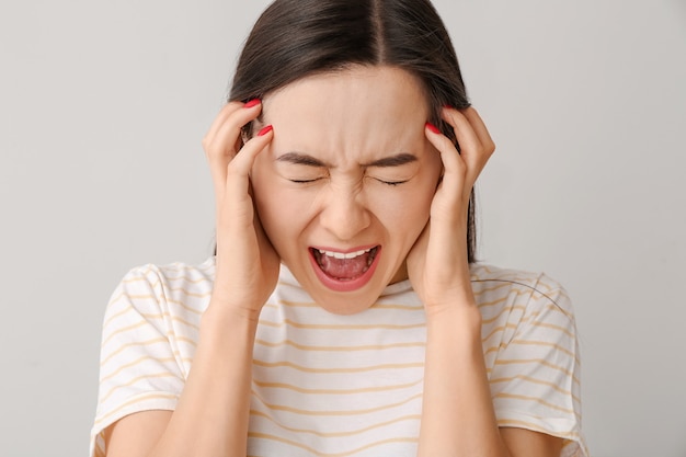 Retrato de mujer joven gritando en gris