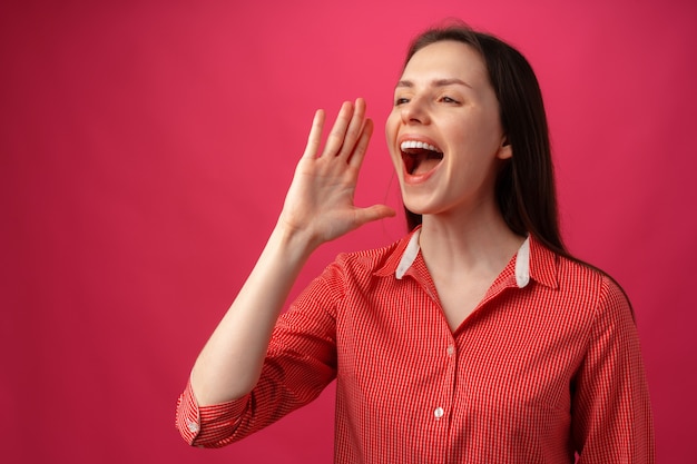 Retrato de mujer joven gritando sobre fondo rosa
