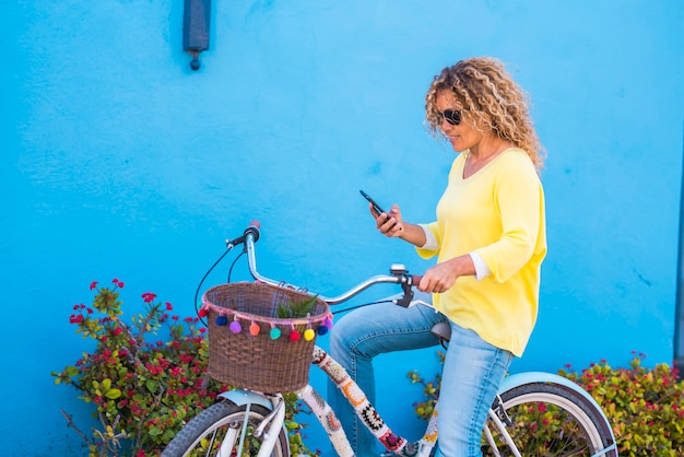 Retrato de mujer joven hermosa adulta utilizar teléfono y conexión a Internet en actividades de ocio al aire libre con la bicicleta