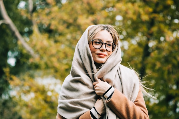 Retrato de mujer joven hermosa en anteojos, disfrutando del clima otoñal en el parque. Mujer caminando en el parque de otoño.