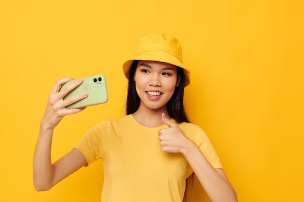 Retrato mujer joven hermosa asiática en un sombrero amarillo y camiseta hablando por teléfono Estilo de vida inalterado