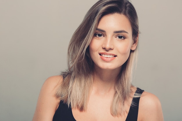 Retrato de mujer joven hermosa en camisa negra sonriendo posando atractiva rubia. Tiro del estudio. Fondo gris.