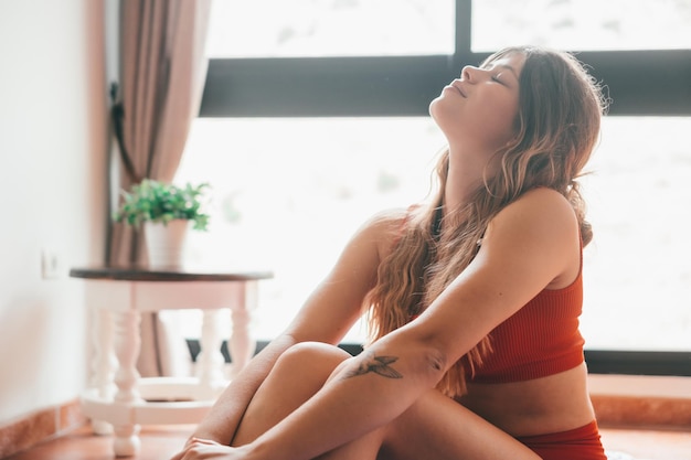 Retrato de una mujer joven y hermosa divirtiéndose y relajándose practicando yoga y haciendo ejercicios en casa sola en el suelo