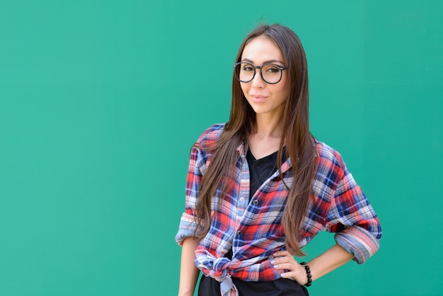 Retrato de mujer joven hermosa hipster con anteojos contra la pared azul