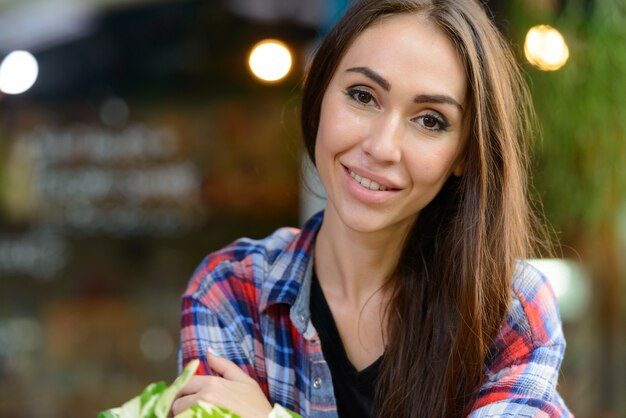 Retrato de mujer joven hermosa hipster relajante en la cafetería al aire libre