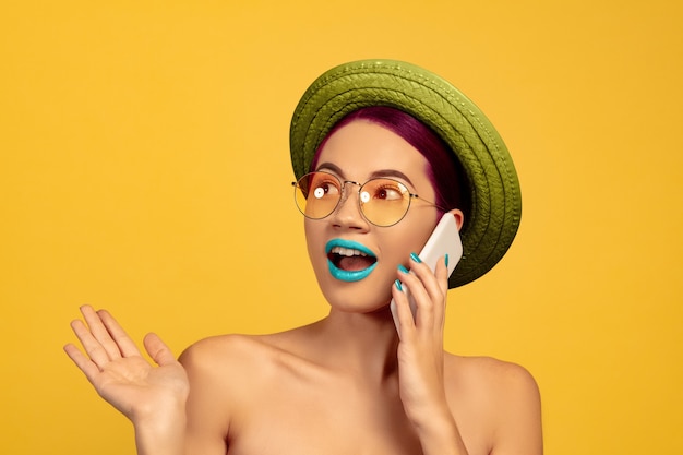 Retrato de mujer joven hermosa con maquillaje brillante aislado en la pared amarilla del estudio