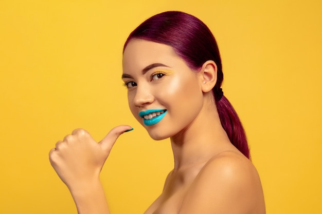 Retrato de mujer joven hermosa con maquillaje brillante aislado sobre fondo amarillo studio