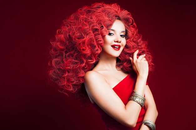 Retrato de mujer joven hermosa con el pelo rojo en la pared roja