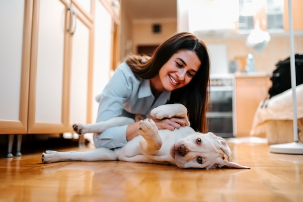 Foto retrato de la mujer joven hermosa con el perro que juega en casa.