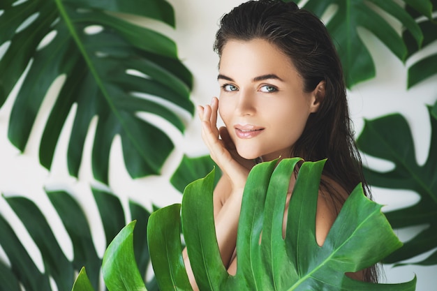 Foto retrato de mujer joven y hermosa con piel suave perfecta en hojas tropicales