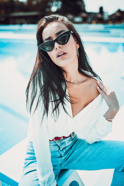 Retrato de mujer joven y hermosa posando junto a la piscina