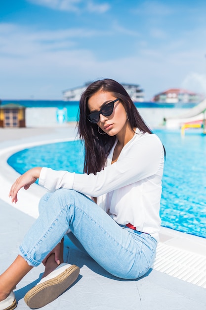 Retrato de mujer joven y hermosa posando junto a la piscina