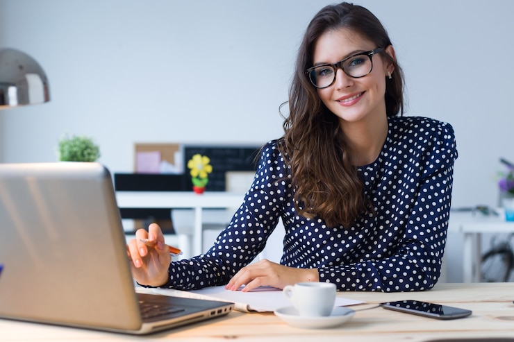 Foto retrato de mujer joven hermosa que trabaja con la computadora portátil en su oficina.