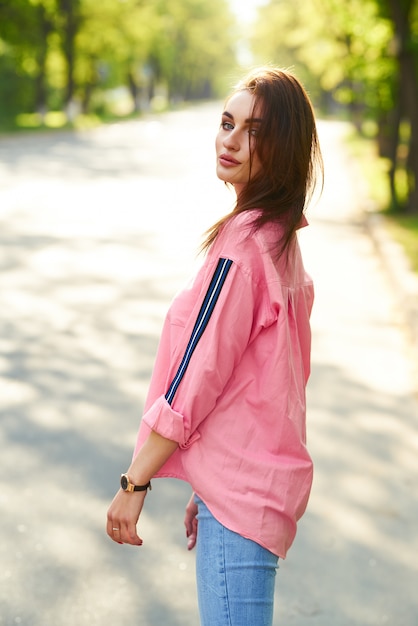 Retrato de mujer joven y hermosa en ropa casual en la calle. vestida con una camisa rosa y jeans. concepto de primavera / verano. tiempo de relajación. Chica de ojos azules. Disfruta de la puesta de sol en la calle