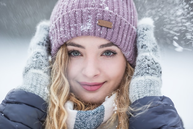 Retrato de mujer joven hermosa en ropa de invierno y nevadas fuertes.