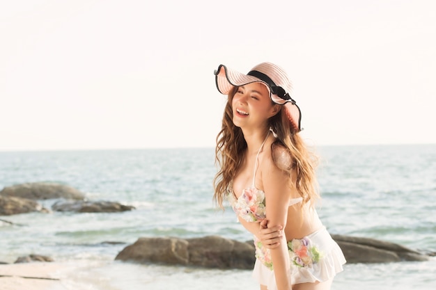 Retrato de mujer joven hermosa sonriente con sombrero de verano con ala grande en la playa.