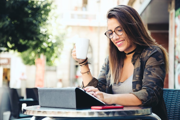 Retrato de mujer joven hermosa con su tableta digital en café.