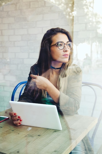 Retrato de mujer joven hermosa con su tableta digital en café.