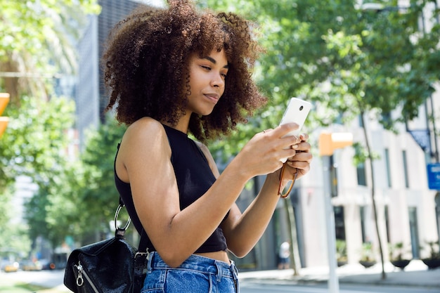 Retrato de mujer joven hermosa con su teléfono móvil en la calle.