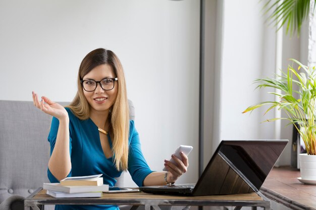 Retrato de mujer joven hermosa en vasos con portátil, telefoto