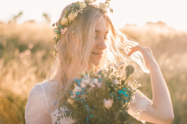 Retrato de mujer joven hermosa con un vestido blanco en estilo boho con una corona de flores en el verano