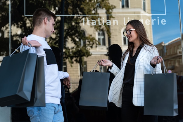 Retrato de mujer joven y hombre con bolsas de la compra. Concepto de compra exitoso. Pareja joven después de hacer compras. Viernes negro.