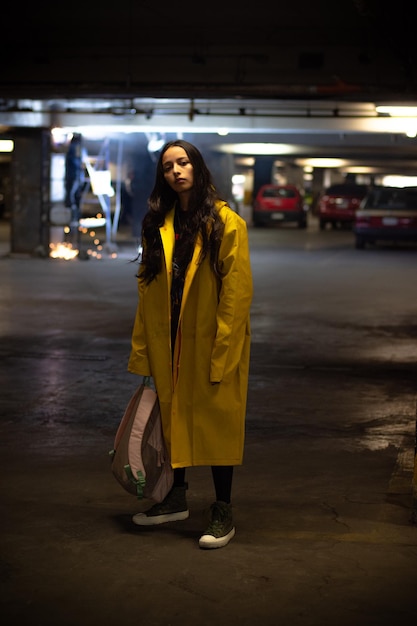 Retrato de una mujer joven con impermeable industrial en el estacionamiento