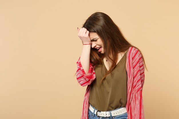 Foto retrato de mujer joven insatisfecha llorando en ropa casual poniendo la mano en la cabeza aislada sobre fondo de pared beige pastel en estudio. personas sinceras emociones, concepto de estilo de vida. simulacros de espacio de copia.