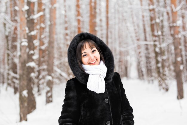 Retrato de mujer joven en invierno. Hermosa joven en un bosque de invierno blanco.