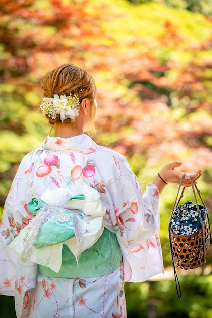 Foto retrato de una mujer joven con kimono de verano yukata con fondo borroso suave en un jardín japonés