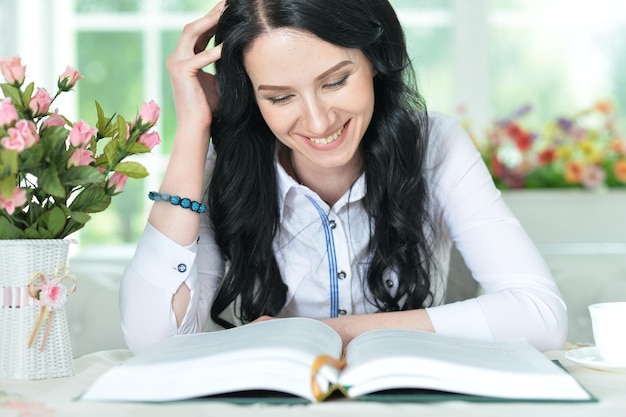 Retrato de una mujer joven leyendo un libro grande e interesante