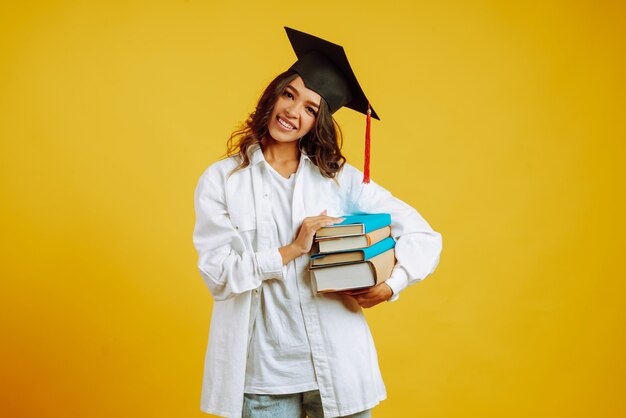 Retrato de mujer joven con libros posando en amarillo.